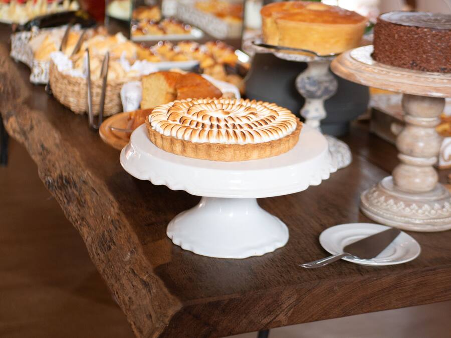 A buffet table with various desserts and a white cake on a pedestal.