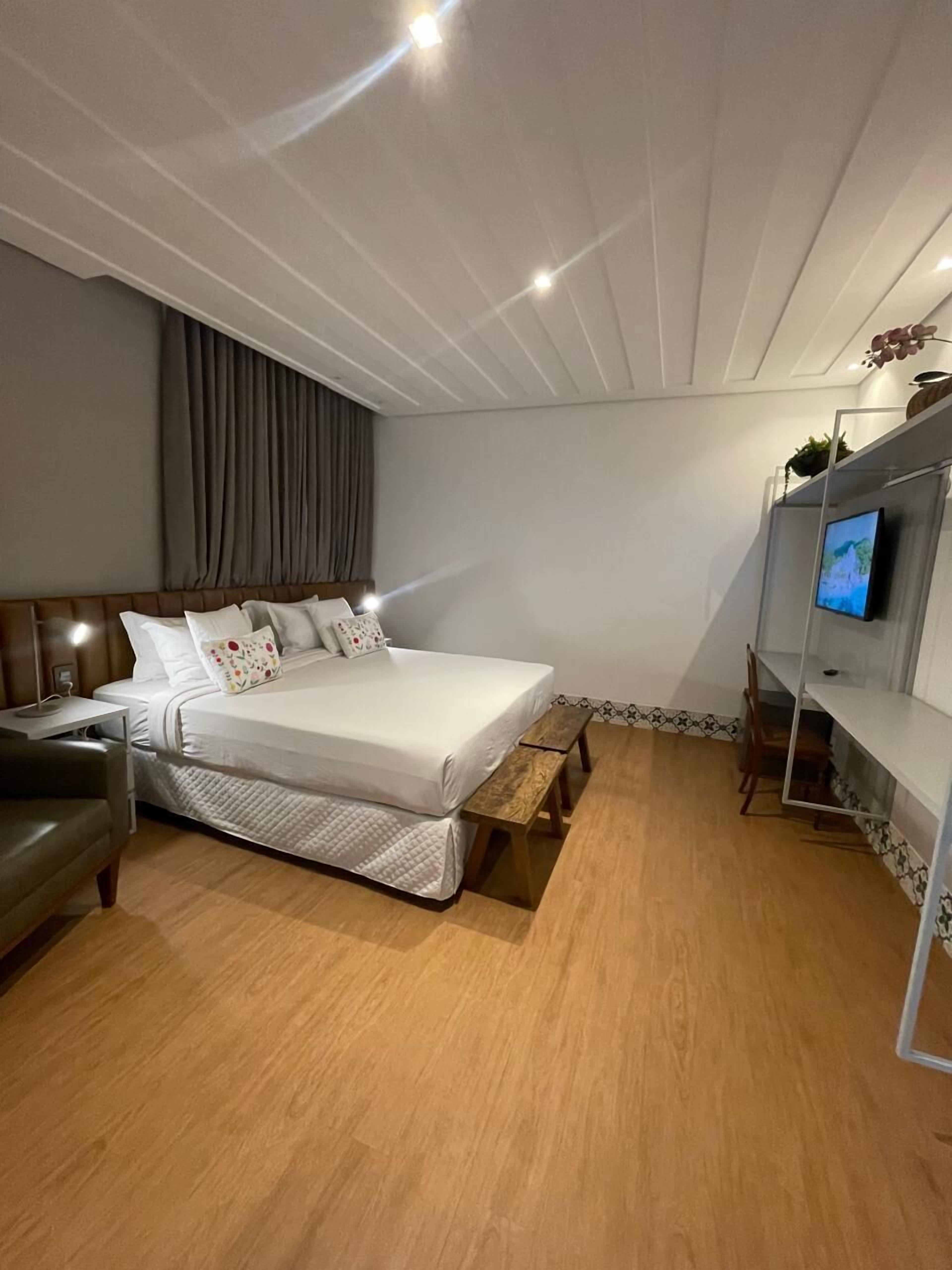 A modern bedroom with a bed, bedside table, and a TV mounted on the wall.