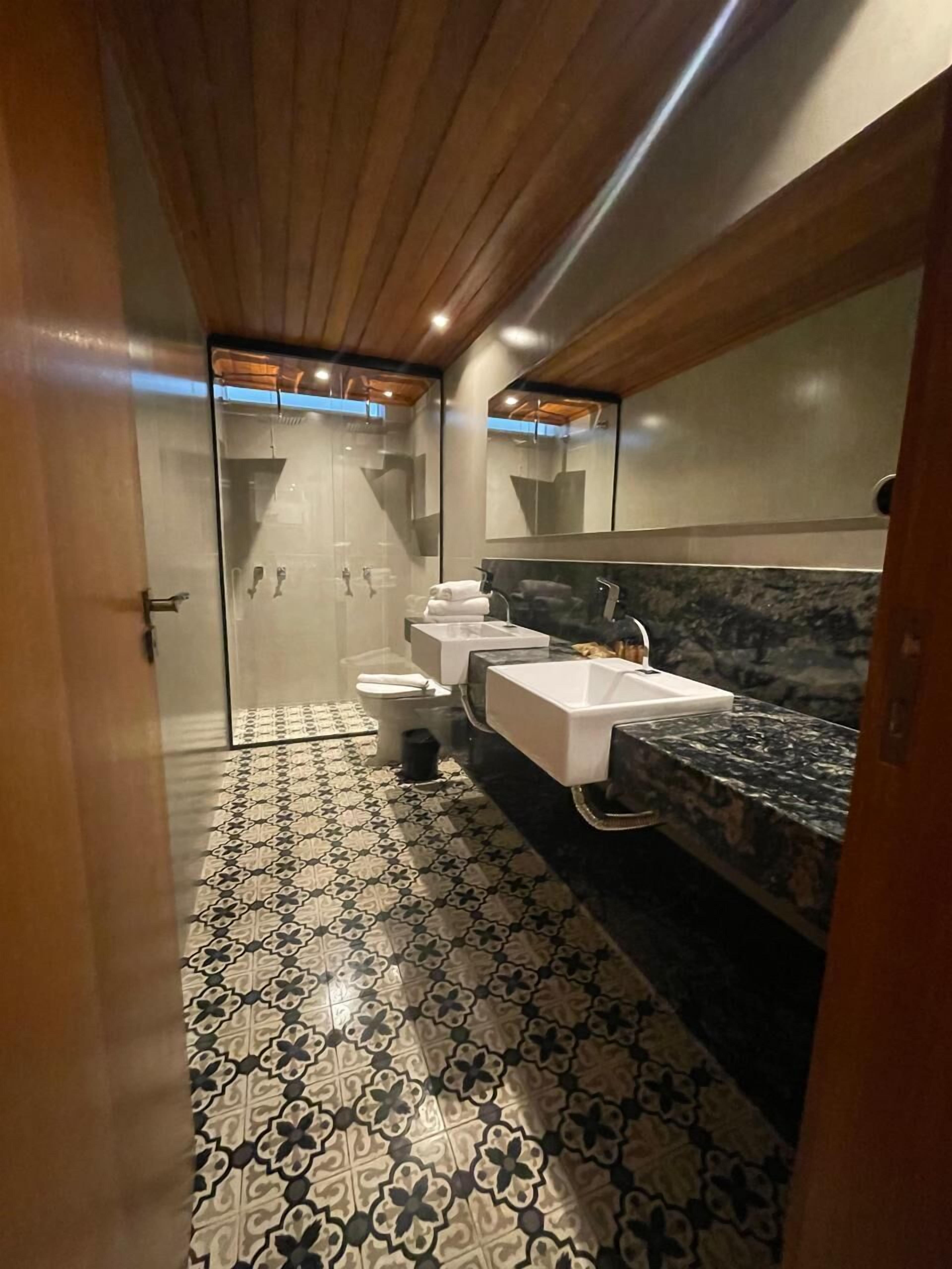 Ein modernes Badezimmer mit Duschkabine aus Glas, einer weißen Toilette, einem weißen Waschbecken und einer Marmorarbeitsplatte.