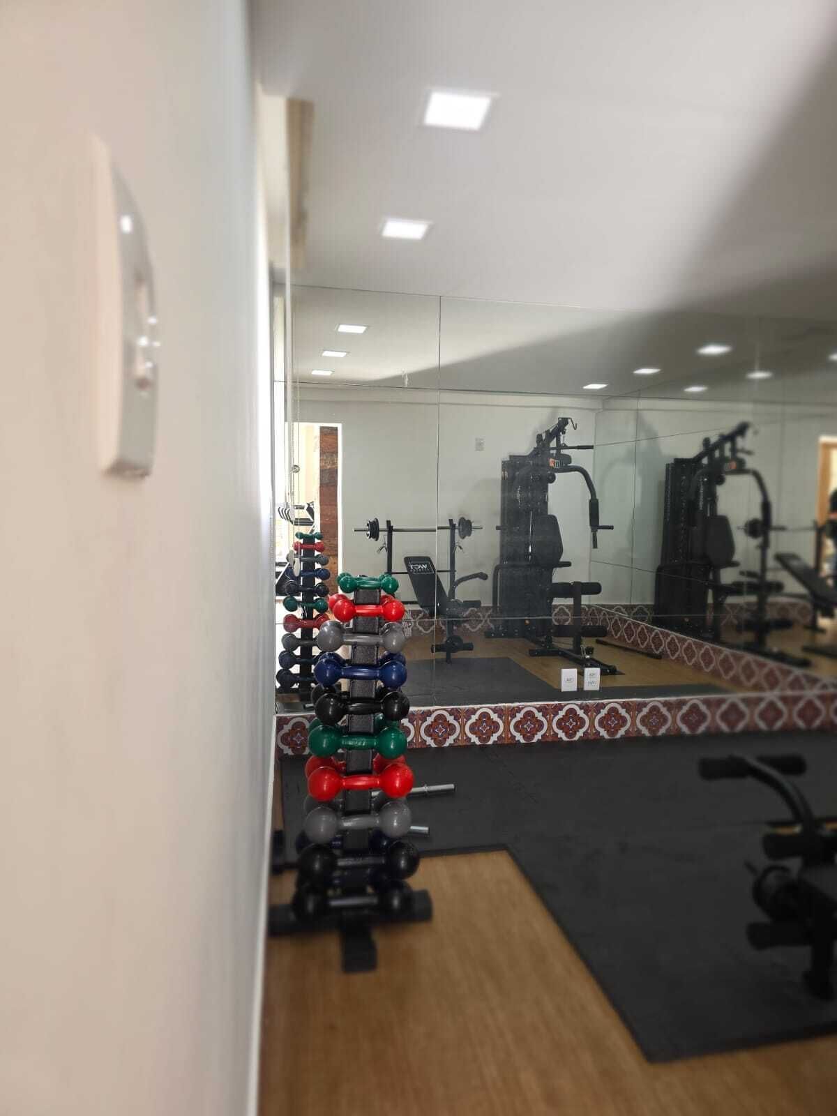 Une salle de sport équipée de divers appareils d’exercice, d’un miroir et d’un sol à motifs.