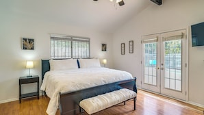 Ein Schlafzimmer mit einem großen Bett, einer Bank, einem Nachttisch und einem Fenster mit Jalousien.