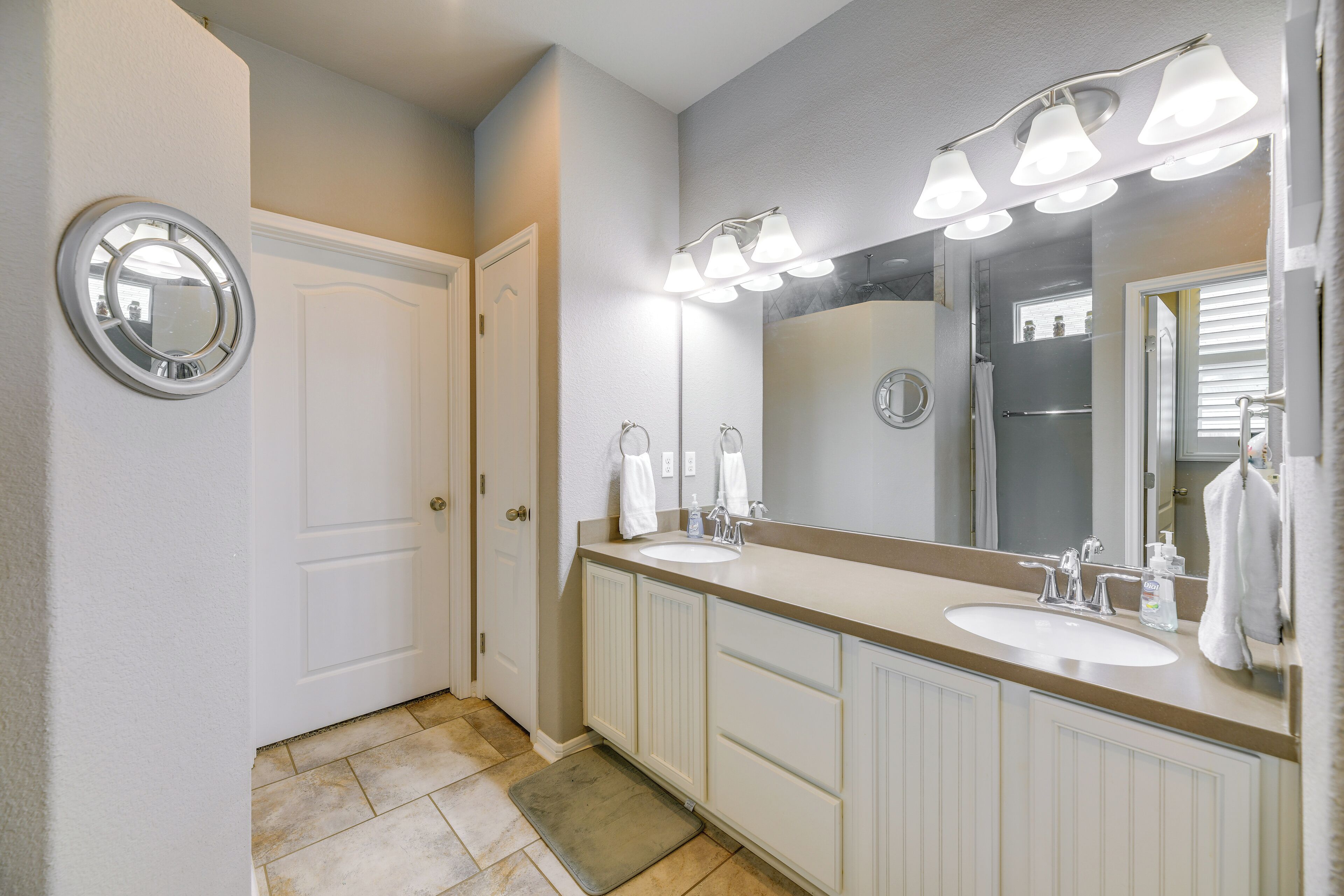 A bathroom with two sinks, a large mirror, and a shower.