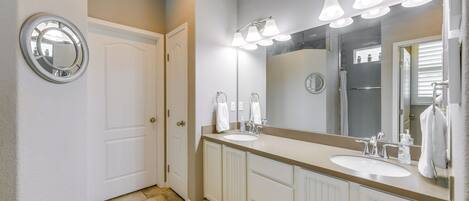 A bathroom with two sinks, a large mirror, and a shower.