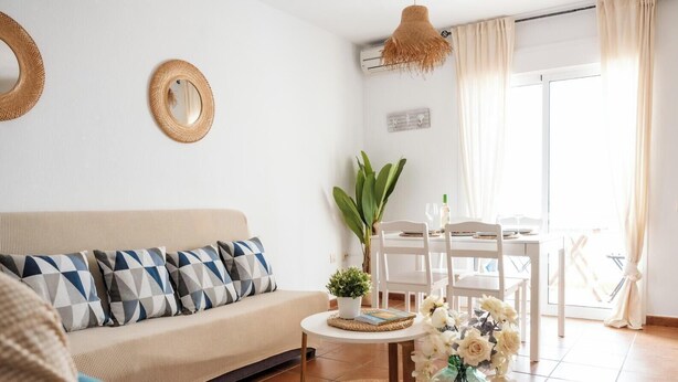 Uma sala de estar com sofá, mesa de jantar e luminária pendente.