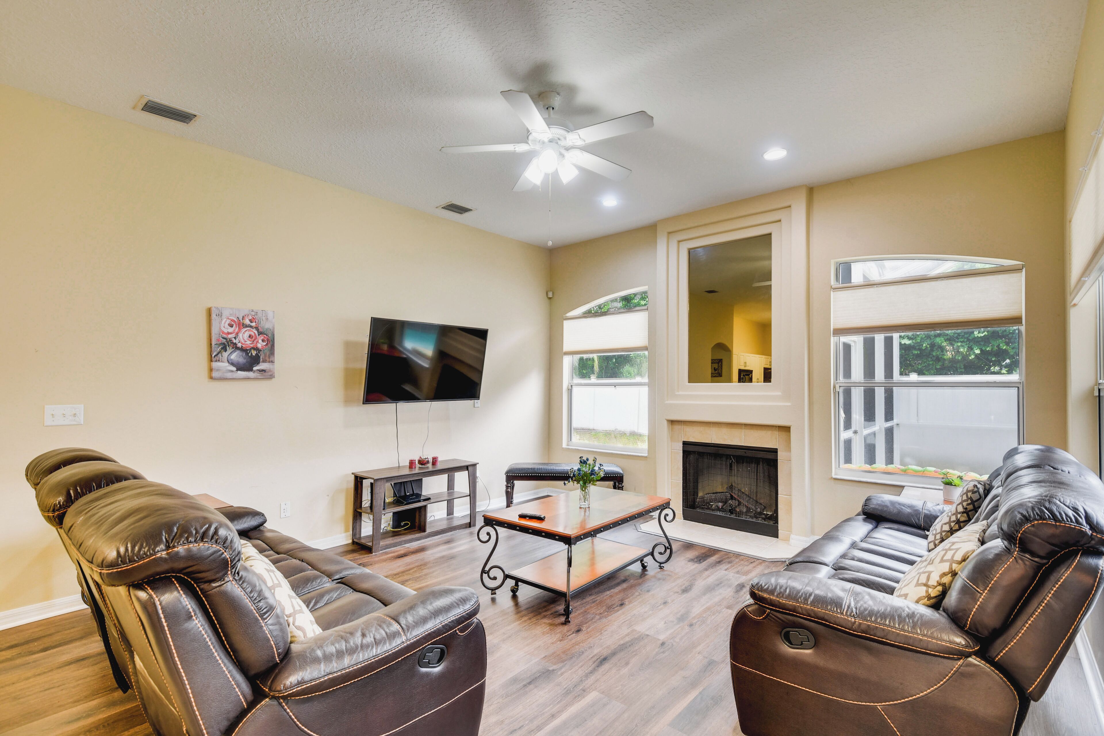 A living room with leather sofas, a wooden coffee table, a flat-screen TV, and a fireplace.