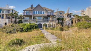 A beachfront property with a wooden pathway leading to a gated entrance, surrounded by sand and vegetation. - Spacious Isle of Palms Home w/ Ocean Views! (Isle of Palms)