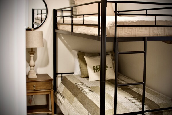 A bunk bed with a quilted blanket and pillows, a bedside table with a lamp, and a mirror on the wall. - Relax Near the Lake less than 2 miles from JP Coleman State Park (Iuka)