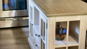 Une cuisine équipée d’appareils électroménagers en acier inoxydable, d’un îlot central en bois doté de rangements et d’un distributeur d’eau.