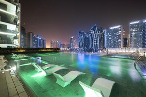 A modern hotel pool area with a city skyline in the background.