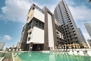 A modern hotel with a rooftop pool, large windows, and a prominent vertical structure.