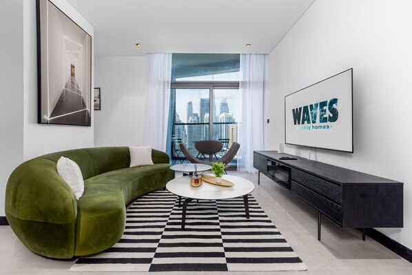 A modern living room with a green sofa, a round coffee table, and a black and white striped rug.