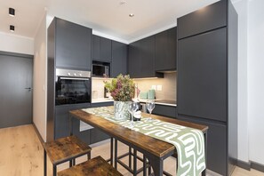A modern kitchen with dark cabinetry, a wooden table, and a bench.