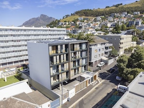 A multi-story building with a modern architectural design, featuring balconies and a parking area.