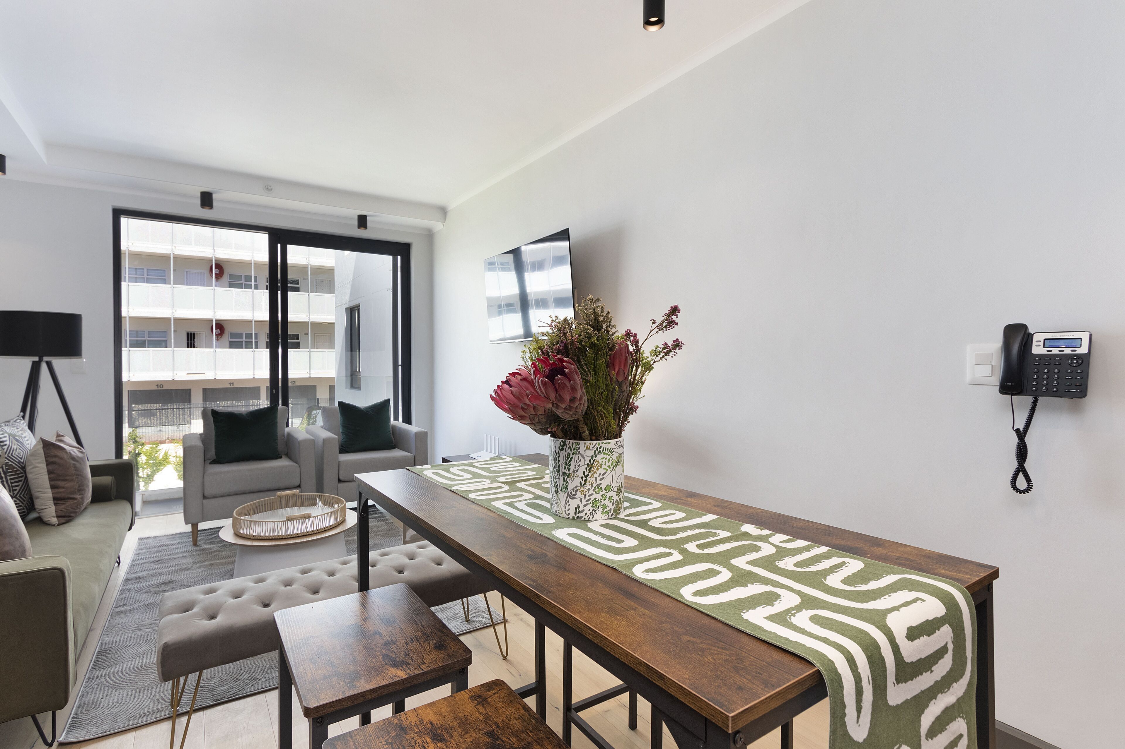 Un salon moderne avec un canapé, une table basse et une table à manger agrémentée d’un chemin de table décoratif.
