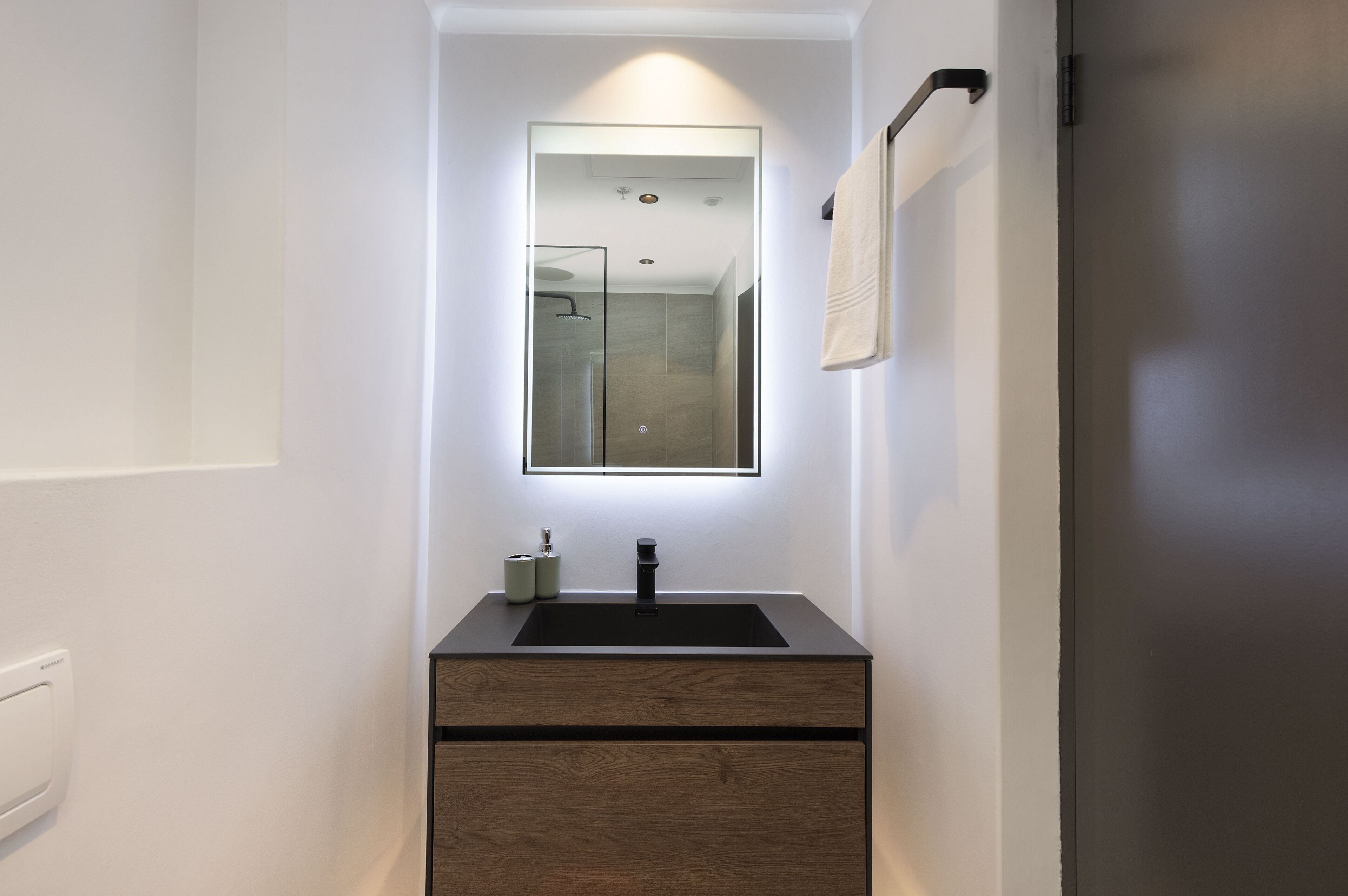 A modern bathroom with a glass shower enclosure, a black sink, and a mirror above it.