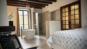 Un dormitorio con una cama grande, una bañera y una ducha. Hay una ventana con cortinas, un techo de madera y un muro con diseño.