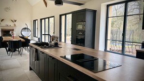 Una cocina moderna con una isla grande, armarios negros y vistas al exterior.