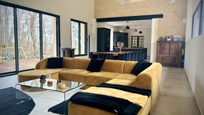 Una sala de estar moderna con un sofá amarillo, una mesa de centro de vidrio y ventanas amplias.