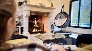 Una sala de estar con chimenea, una mesa de centro de vidrio y una silla negra.