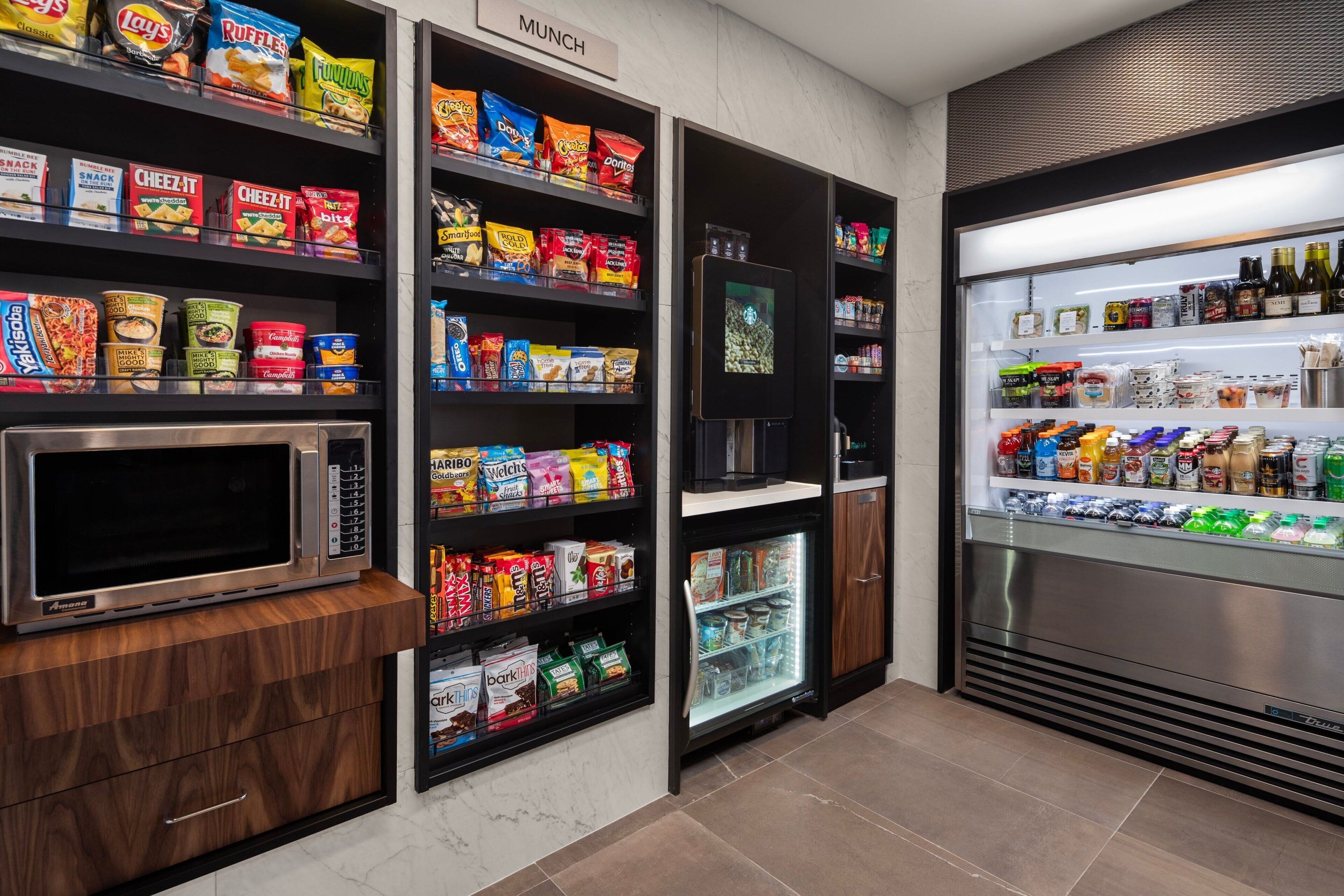 A snack and beverage kiosk with microwaves, refrigerated sections, and shelves stocked with snacks and drinks.