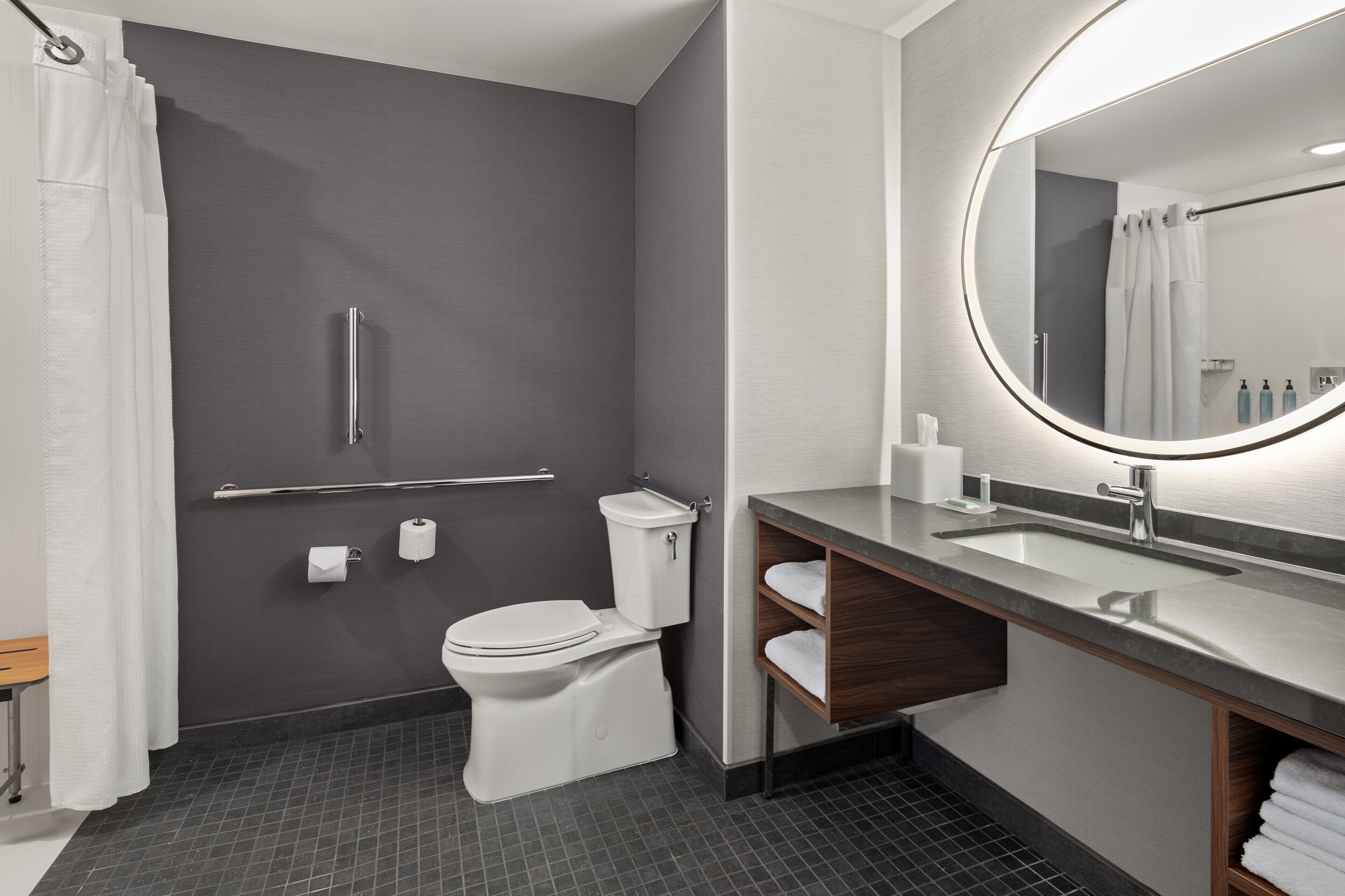 A modern bathroom with a toilet, sink, and mirror.