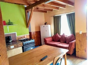 A compact kitchen with a gas stove, a refrigerator, and a wooden table. - Altos de Pichilemu 1 (Pichilemu)