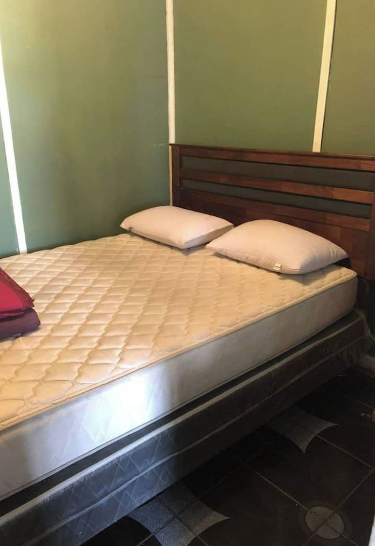 A single bed with a wooden headboard, a quilted mattress, and two pillows.