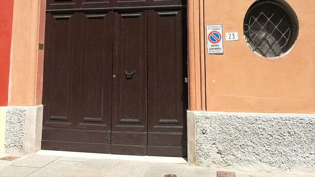 A brown double door with a decorative metal arch, a window with shutters, and a no parking sign. - CA POMPOSA bed & relax  (Modena)