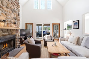 A living room with a stone fireplace, a television, a sofa, and a coffee table. - Union Pier Home with Private Pool and Association Beach! (Union Pier)