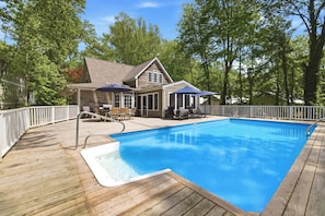 A swimming pool with a wooden deck, a covered seating area, and a house with a gabled roof. - Union Pier Home with Private Pool and Association Beach! (Union Pier)