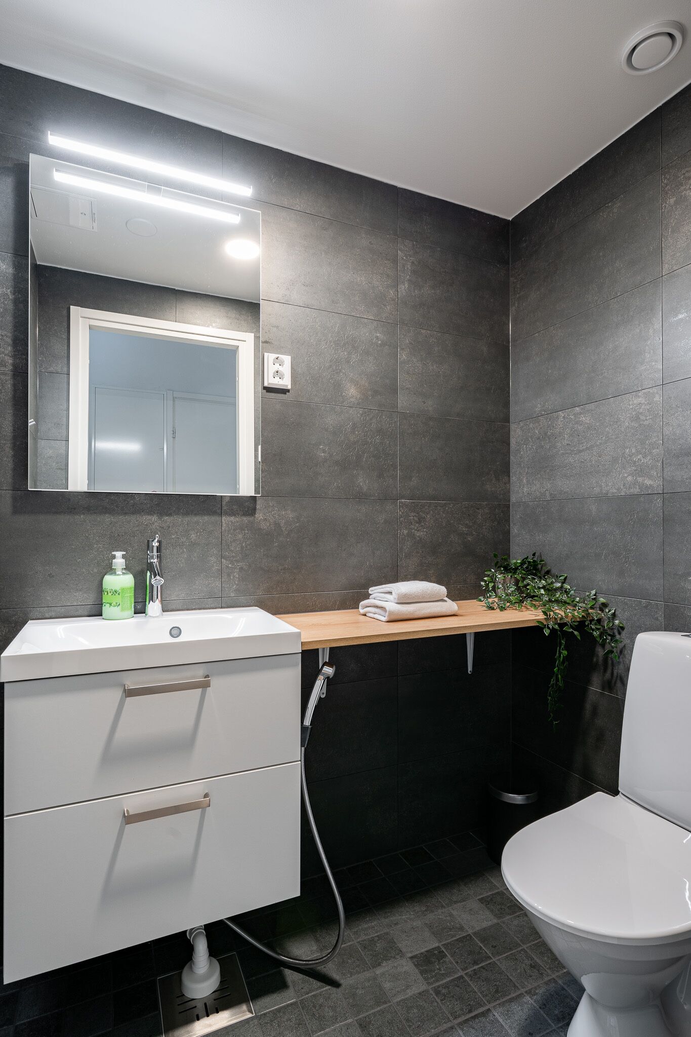Ein modernes Badezimmer mit Waschbecken, Spiegel und Toilette in Weiß.