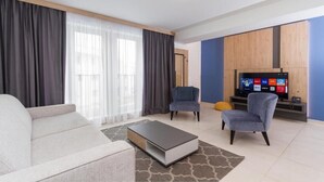 Una sala de estar moderna con un sofá, dos sillones, una mesa de centro y un televisor.