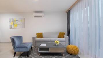 A modern living room with a grey sofa, a blue armchair, and a coffee table with a vase of flowers.