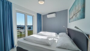 Un hotel moderno con una cama grande, vista al mar y un cuadro en la pared.