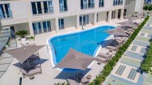 Un hotel moderno con piscina, tumbonas y sombrillas.