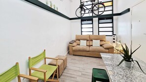 En moderne stue med sofa, stole, en cykel og en potteplante.