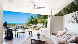 A balcony with a view of the sea, a hammock, a grill, and a sofa. - Picture Perfect On Azure (Airlie Beach)