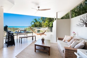 A balcony with a view of the sea, a hammock, a grill, and a sofa. - Picture Perfect On Azure (Airlie Beach)