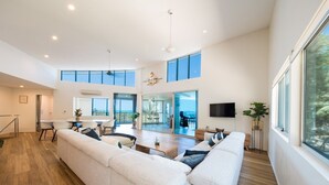 A spacious living area with a large sofa, dining table, and a view of the outdoors. - Picture Perfect On Azure (Airlie Beach)