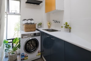 A laundry area with a washing machine, a sink, and cabinets.