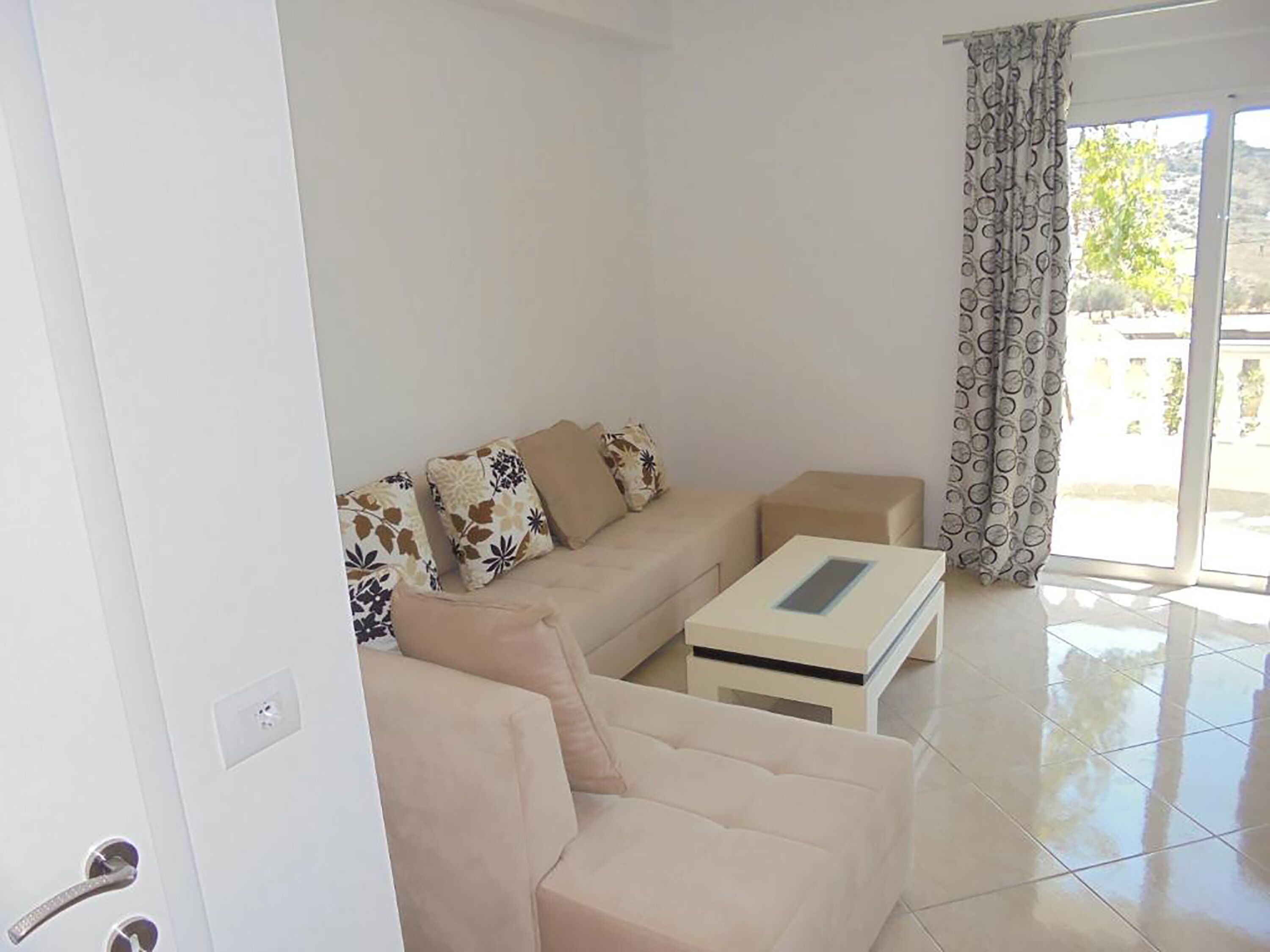 A living room with a beige sofa, a coffee table, and patterned cushions.