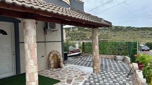 A covered outdoor area with stone flooring and a pergola structure.
