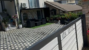 A two-story house with a balcony, a covered patio, and a gated entrance.