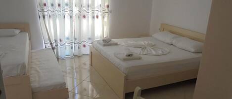 A hotel room with a double bed, a single bed, and a chair.
