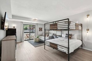 Habitación con literas, un escritorio, una silla, una mesita y vista al exterior.