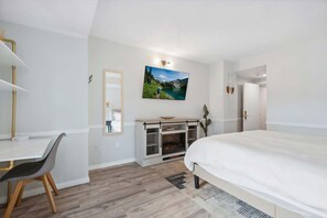 Quarto com cama, escrivaninha, espelho, lareira e um quadro na parede.