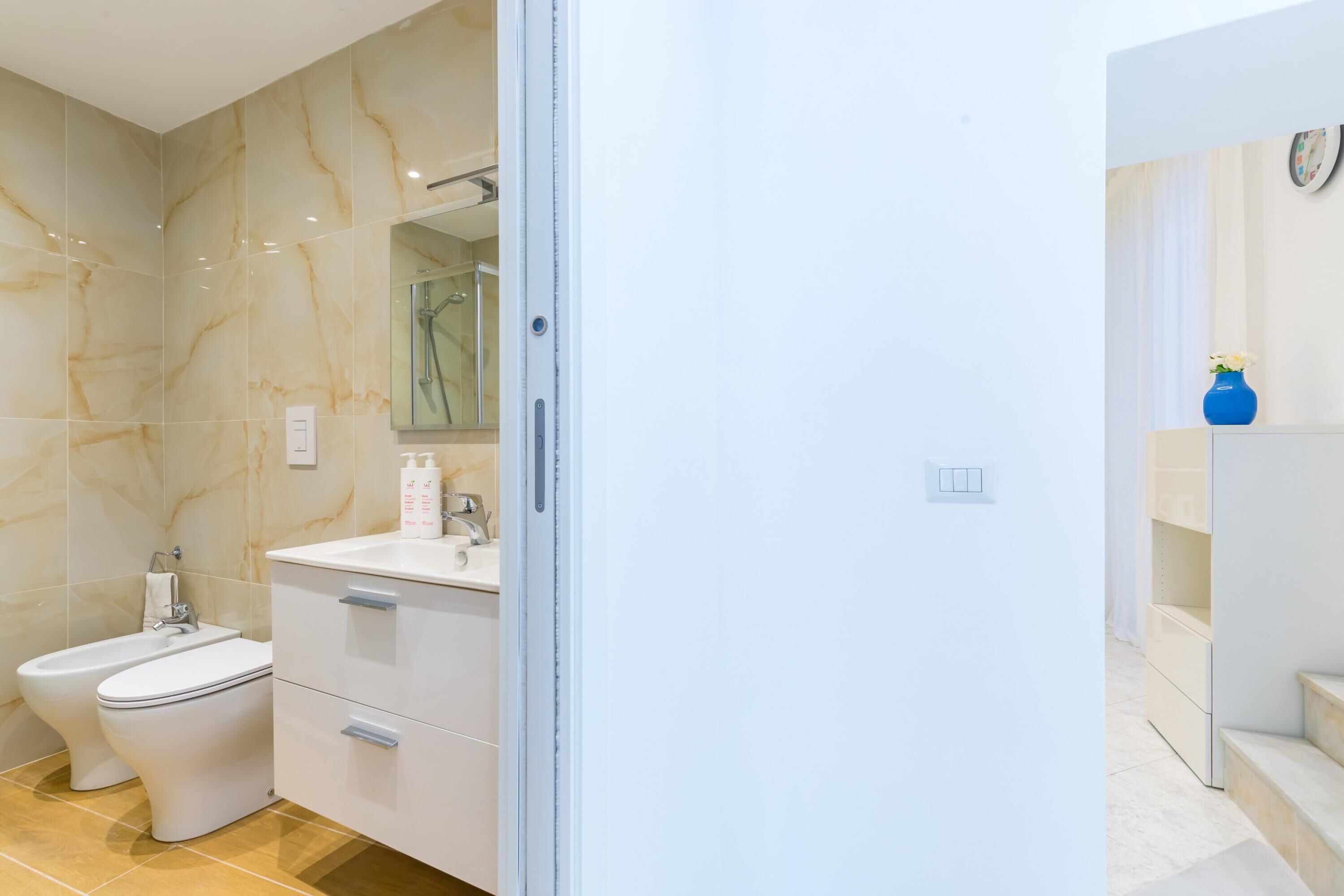 A modern bathroom with a bidet, a sink, and a mirror.