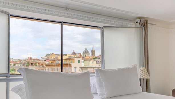Habitació d'hotel amb una finestra gran que ofereix vistes a edificis històrics i una estructura en forma de cúpula.