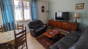 Een woonkamer met een bank, een salontafel, een televisie en een houten kast.