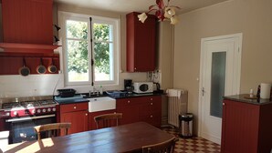 Een keuken met een fornuis, magnetron, spoelbak en een eettafel met stoelen.
